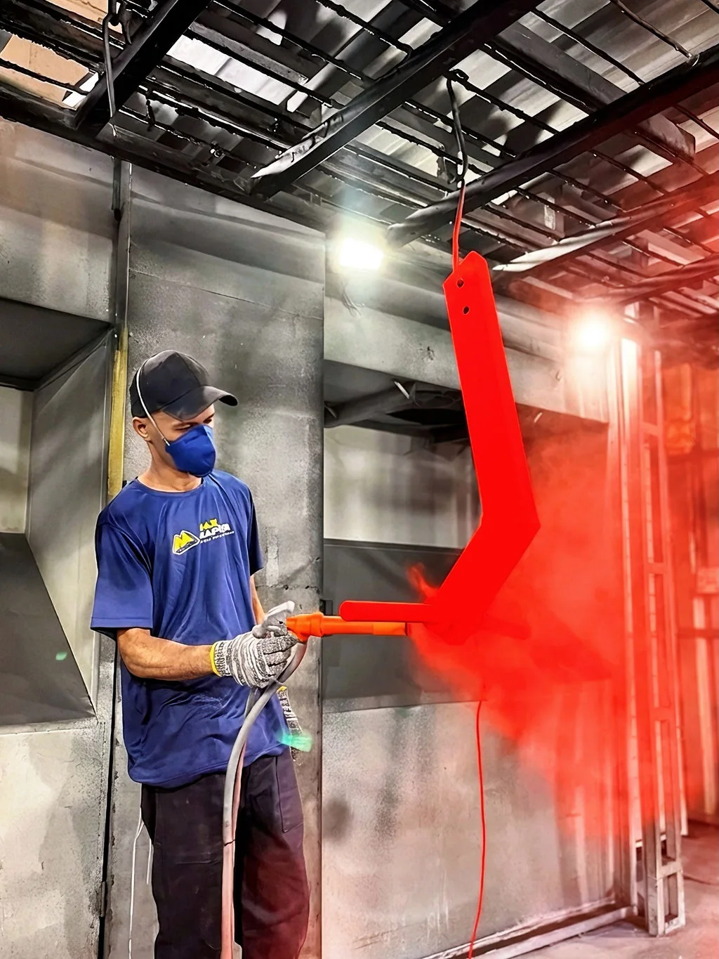 Profissional da Max Master aplicando tinta vermelha em estrutura metálica