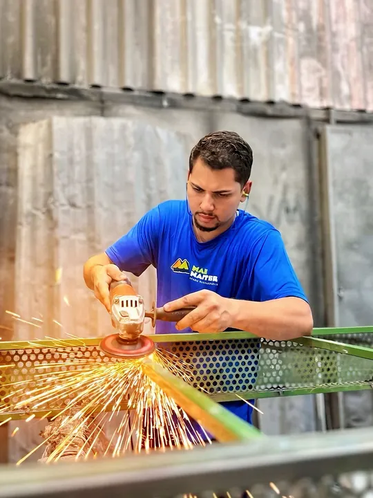 Profissional realizando preparação mecânica em uma estrutura metálica